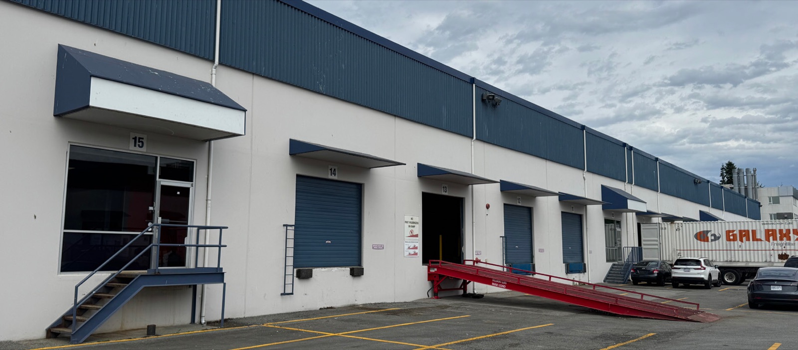 Unit 15 entrance at 403 East Kent Avenue North with office door, dock doors and steel grade ramp