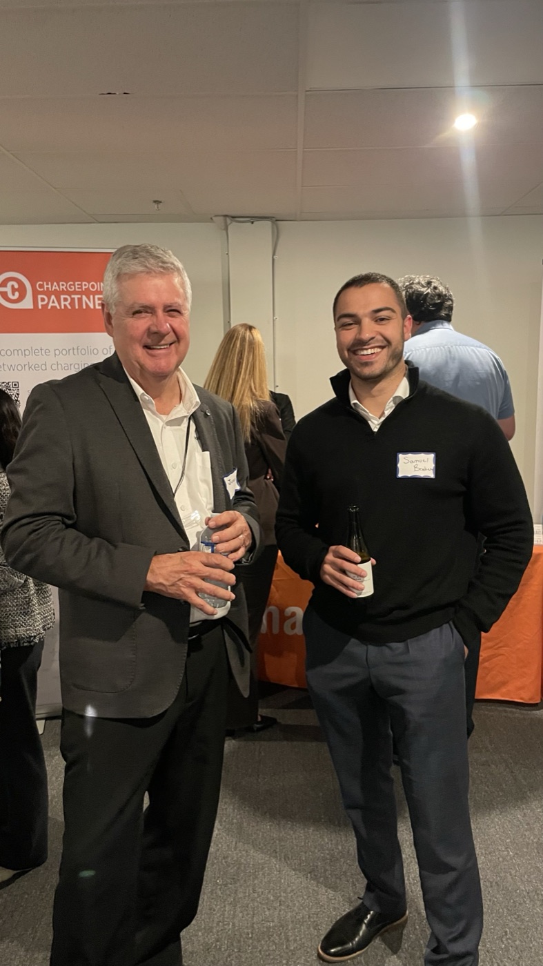 Samuel Brahem standing with a fellow attendee in front of a ChargePoint partner banner at the Foreseeson Technology networking event.